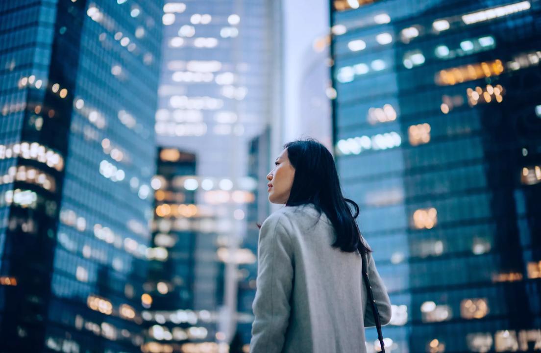 Side view of woman looking up at sky scrapers.