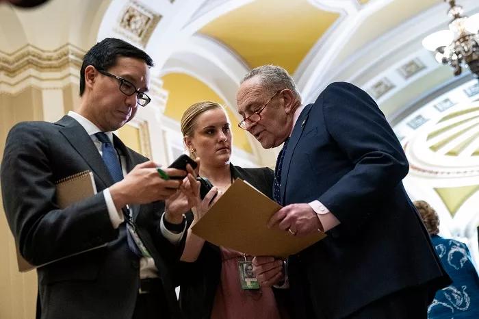 US Senate Majority Leader Chuck Schumer confers with aides before fielding questions on interest rate hikes.