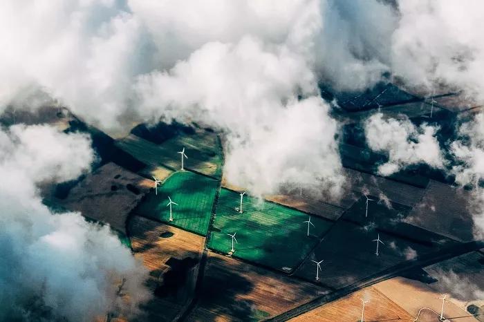 Aerial view through clouds of  windfarm on pastures.